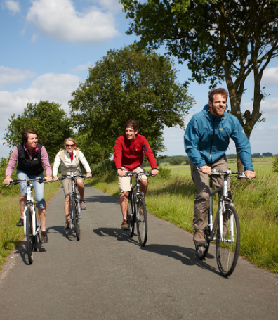 vier fahrradfahrer, fahhradweg, grüne landschaft, blauer himmel